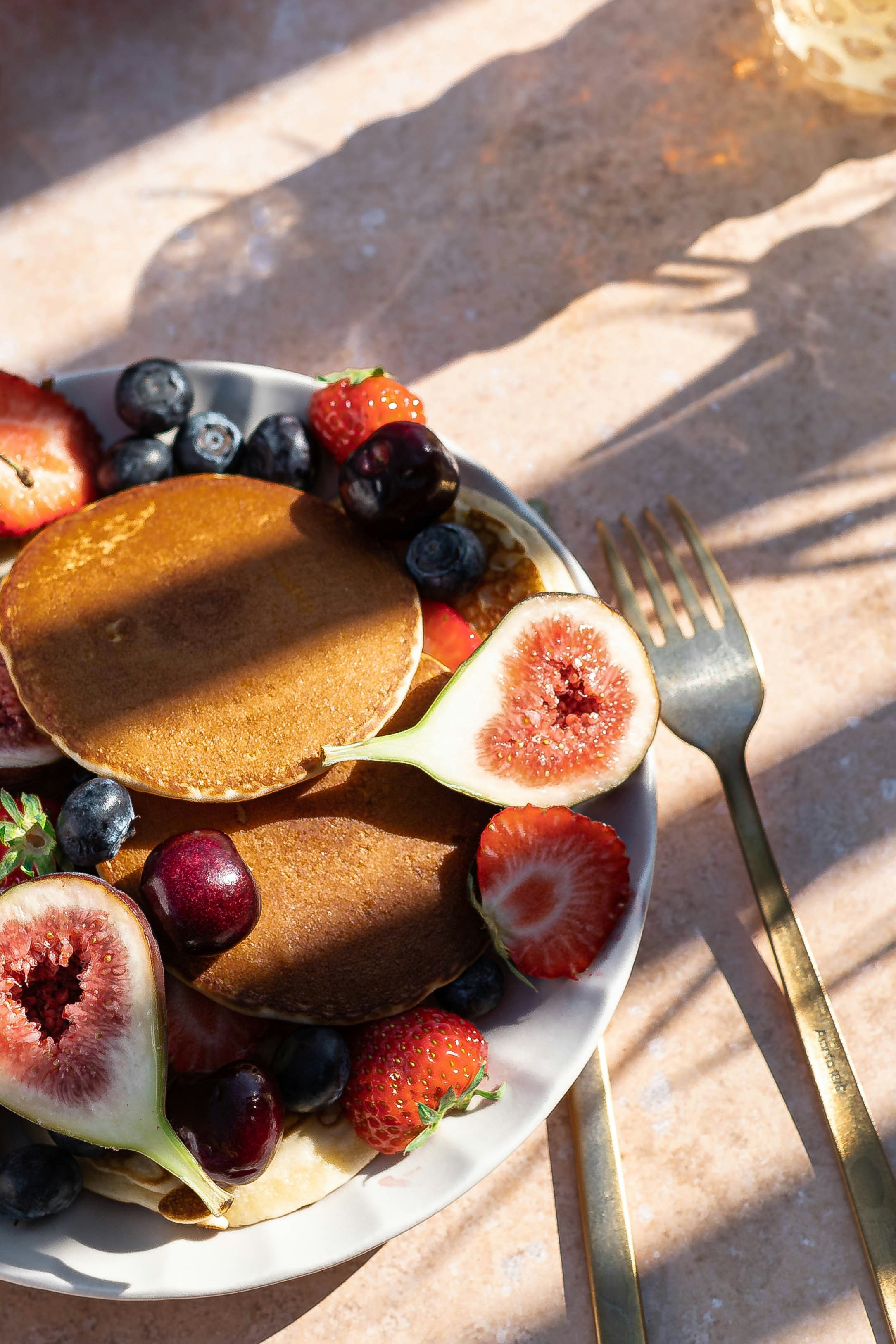 Buckwheat hotcakes with figs, strawberries, blueberries and gold cutlery